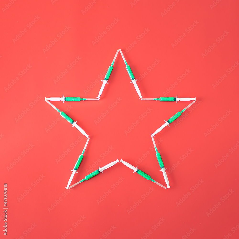 Christmas star made of green vaccine on red background. Minimal New Year and christmas concept. Winter holidays background. Christmas star made of green vaccine on red background. Minimal New Year and christmas concept. Winter holidays background.