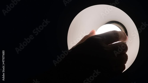 hand screwing light bulb in the darkness