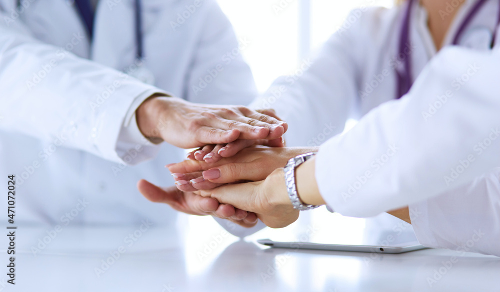 Team of doctors putting hands together, closeup Team of doctors putting hands together, closeup