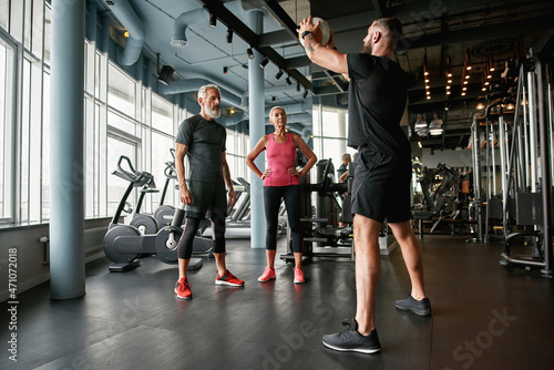 Personal trainer and middle-aged couple at gym