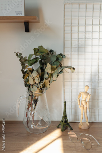 Eucalyptus branches in a glass vase with sunlight shadows on the table. Romantic interior decoration design.