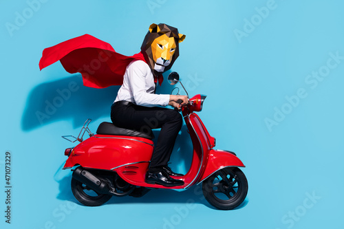 Full length profile side photo of authentic guy in lion mask ride scooter festive theme event party isolated over blue color background