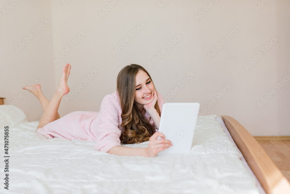 Image of beautiful amazing young woman indoors posing at home in white robe near big windows. Image of beautiful amazing young woman indoors posing at home in white robe near big windows.