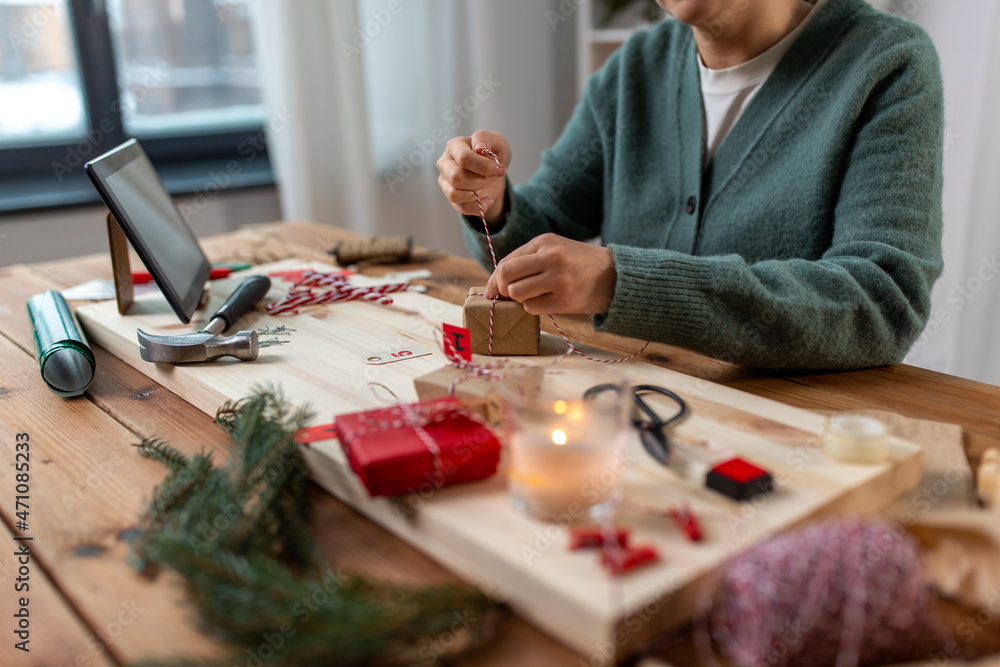 Fototapeta premium winter holidays and hobby concept - close up of woman with box and rope packing christmas gift or making advent calendar at home