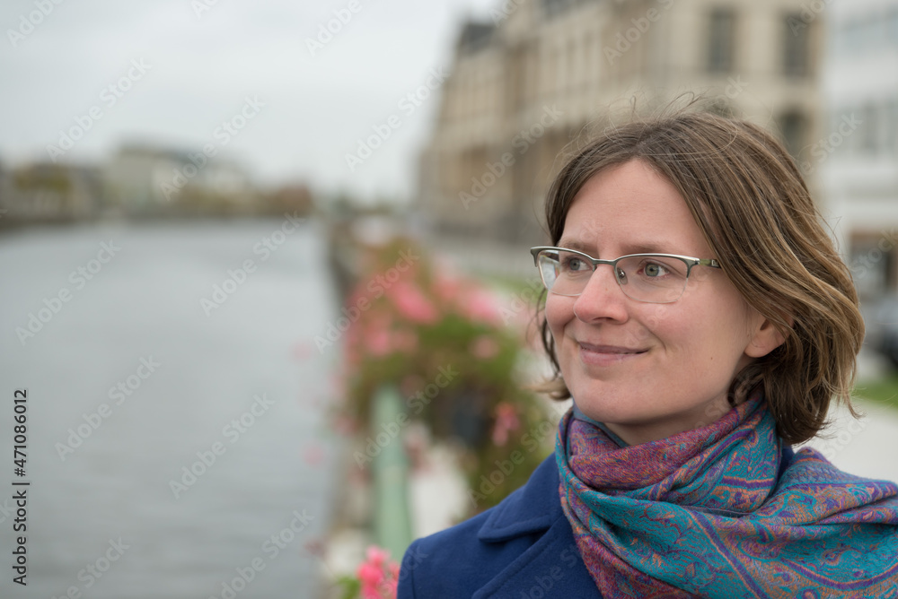 Portrait of a thirty year old white woman with glasses, posing at the water front