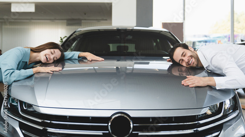Closeup of extremely satisfied happy caucasian young couple family husband and wife hugging embracing their new car, feeling excited after buying expensive auto at auto dealer shop store. © InsideCreativeHouse