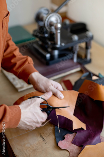 Craftsman cutting natural material use scissors. Working process at leather workshop