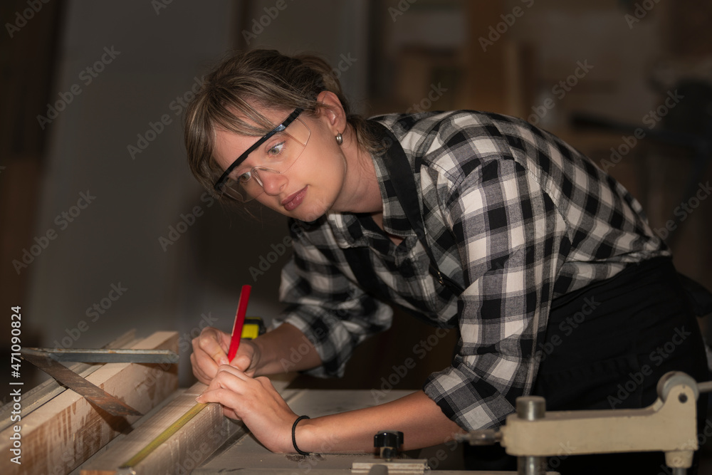 Woman carpenter taking measurement of a wooden plank Woman carpenter taking measurement of a wooden plank