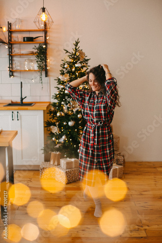 beautiful young woman dancing in a christmas inerie on the background of a christmas tree. photo