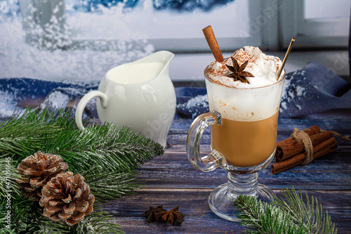 Hot coffee latte with cinnamon sticks, sprinkled with cinnamon. Christmas decorations, branches of a Christmas tree. Holiday concept New Year.