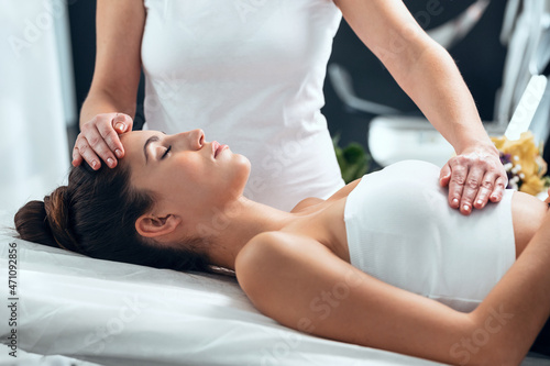 Obraz na plátně Beautiful young woman having reiki healing treatment in health spa center