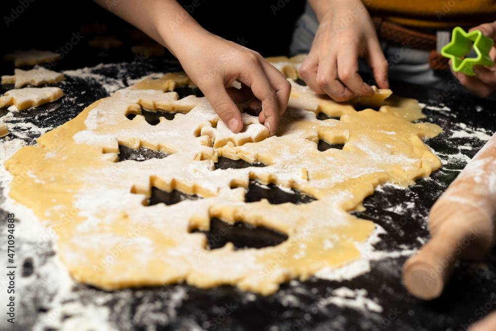 Children cook New Year's cookies together. Carving Christmas trees from dough. Preparation for the holiday. Joint team action.