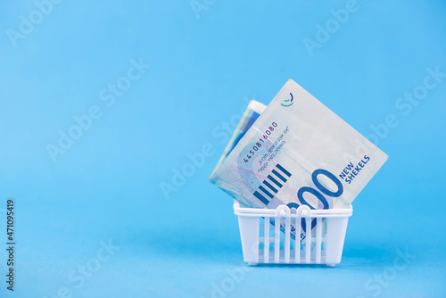 Fotografia Israel money shekel banknotes in shopping cart on blue background