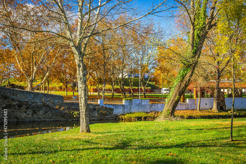 Beautiful park with river and stone bridge in the village of Serta - Portugal. Autumn folliage trees reflecting on the water. Roman ancient bridge over the river photo