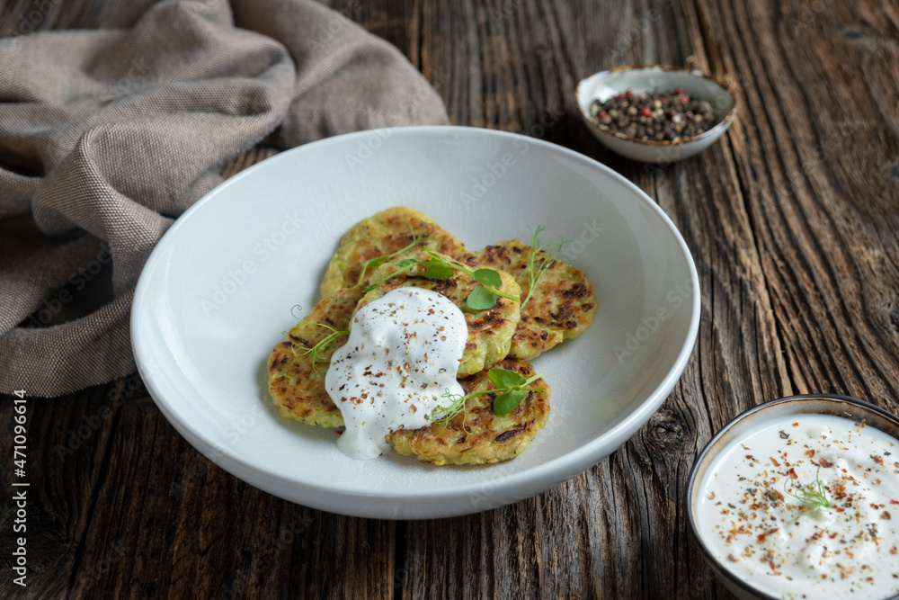 Zucchini pancakes with creamy sauce on a wooden table