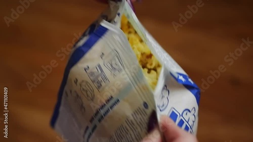 The girl opens a bag of hot, ready-made popcorn, stretching it to the sides.