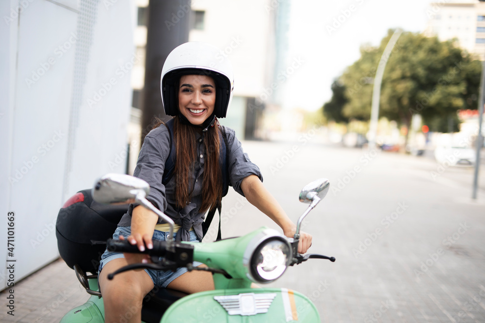 Beautiful woman getting ready for a ride on scooter. Beautiful happy lady having fun outdoors.