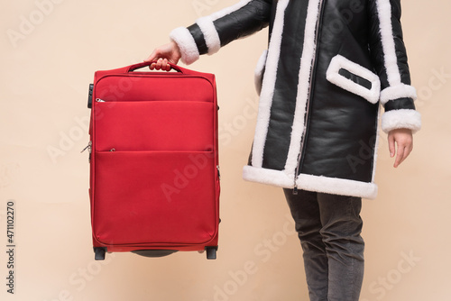 Woman holds in hand a traveling bag on the light background.