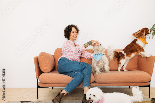 Wall Mural Young woman sitting on a couch with three dogs in living room