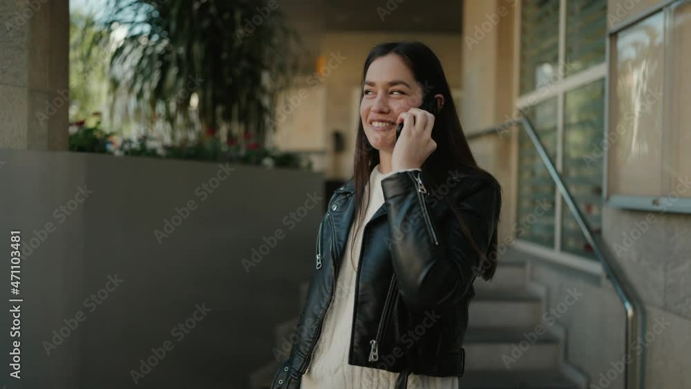 Young hispanic woman smiling confident talking on the smartphone at street