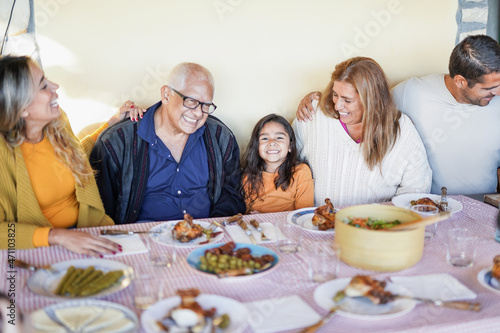 Cheerful latin family eating lunch together at home on patio