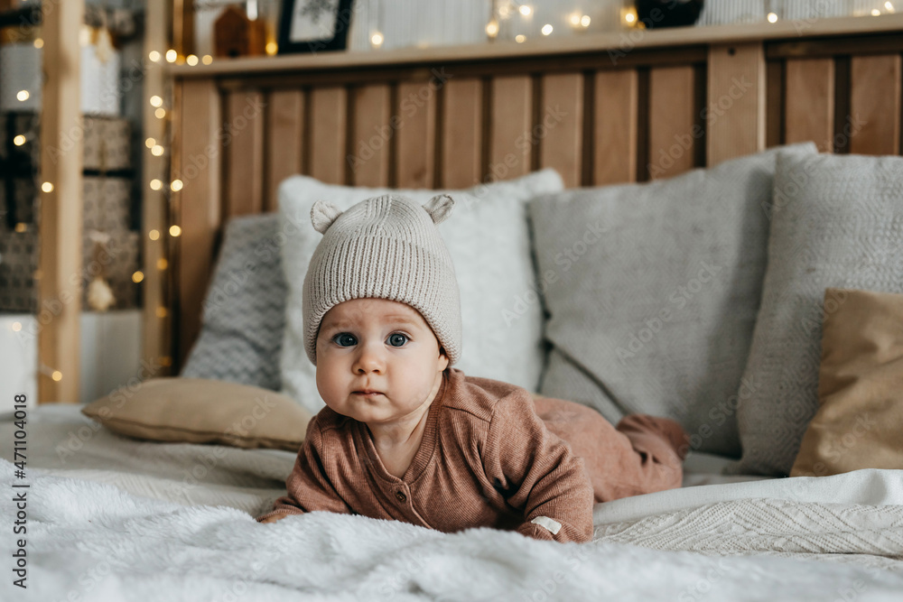 Baby lying on stomach on bed, wearing a knitted beanie with ears. Baby lying on stomach on bed, wearing a knitted beanie with ears.
