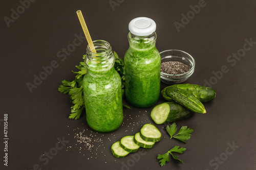 Green smoothie with cucumber in glass bottles. Fresh ripe vegetables, greens, and chia seeds
