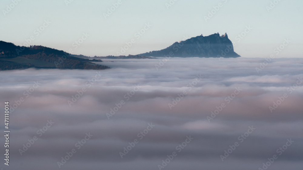 View of the castle of San Marino peeking out from the autumn mist. All seen from Monte delle Cesane in the province of Pesaro and Urbino in the Marche region