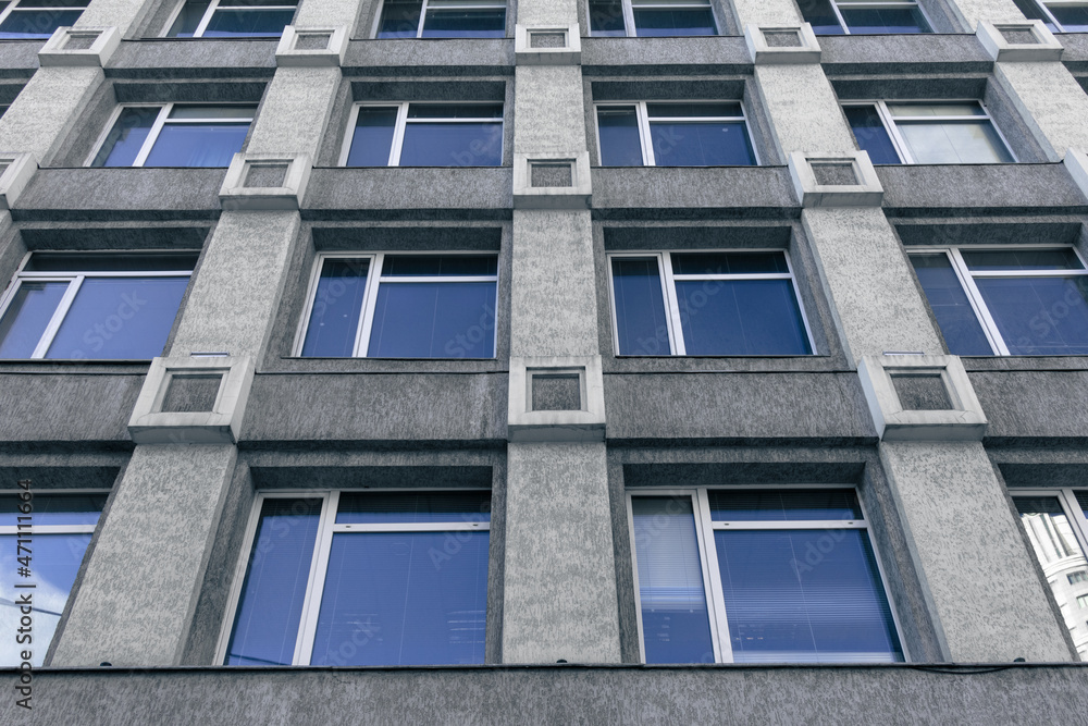 Gray wall with many windows. A background of a bottom view of a building with many windows Gray wall with many windows. A background of a bottom view of a building with many windows