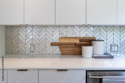 Konstfotografi Modern kitchen detail of chevron pattern silver tile backsplash with sleek white countertop and white cabinets