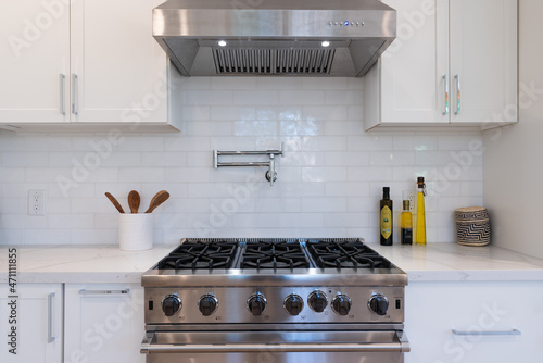 Slika na platnu Modern kitchen details of white marble counter, gas stove, and white tile backsplash