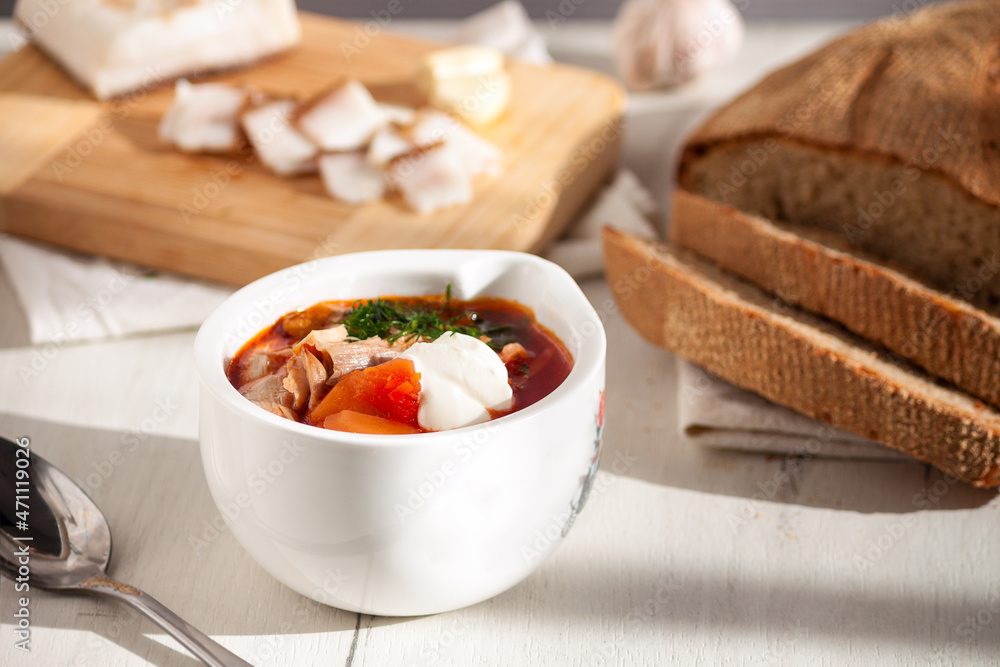 Traditional Ukrainian borscht. Red beet roof soup with homemade bread on white wooden table. Traditional Ukrainian borscht. Red beet roof soup with homemade bread on white wooden table.