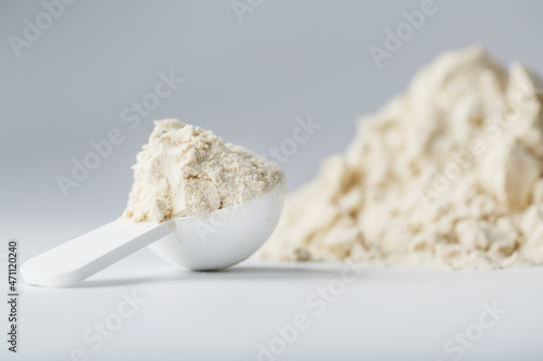 A pile of protein powder with a measuring spoon on a white background. photo