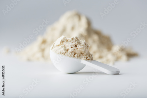 A mountain of soy protein isolate in powder with a measuring spoon on a white background. photo
