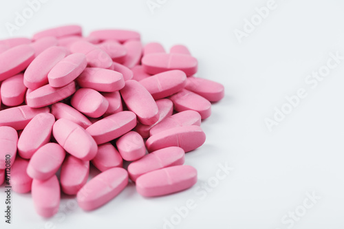 Pink pills with multivitamins on a white background.