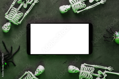Fotografi Four skeletons are lying near the smartphone on a dark background
