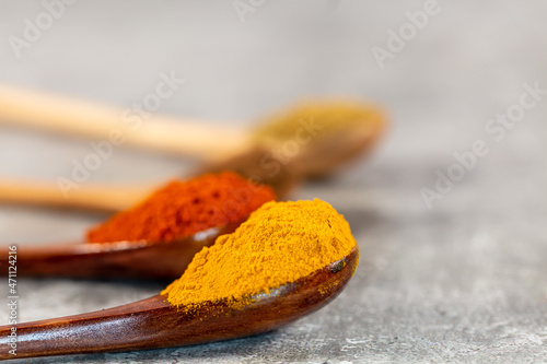 Spoonfuls of vibrant spices against a grey background
