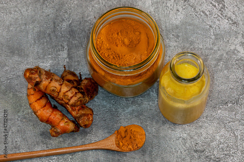 Looking down on an arrangement of turmeric root, powder and milk against a grey background photo