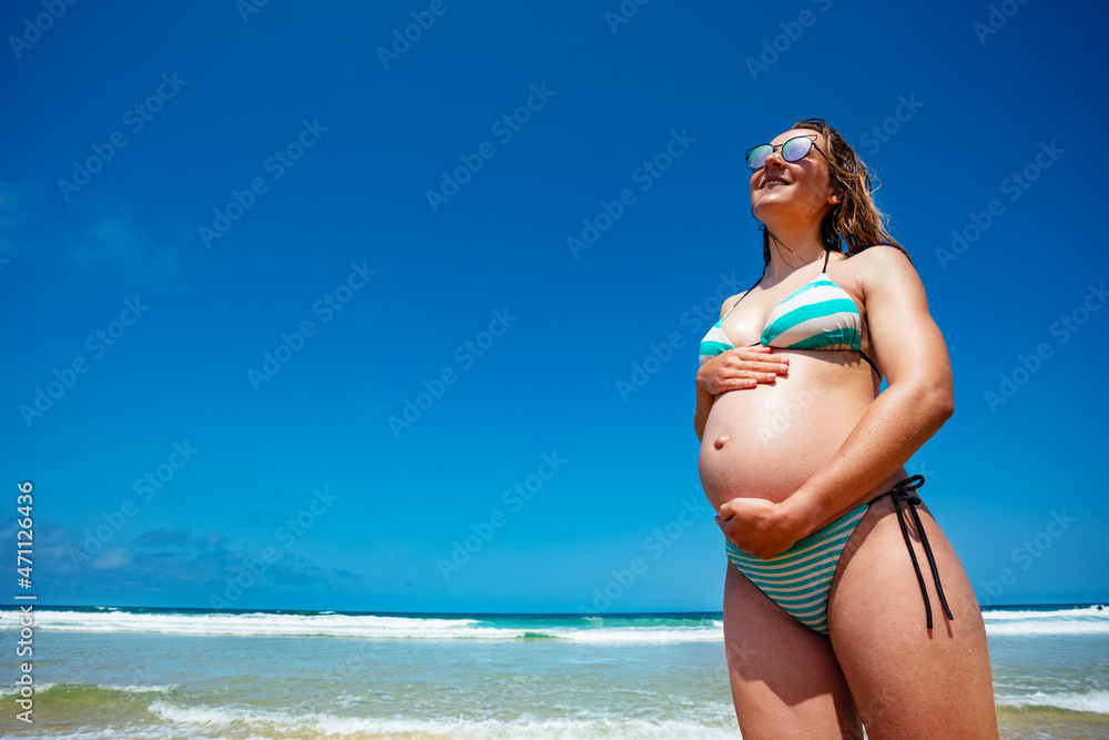 Pregnant woman with big belly on summer beach