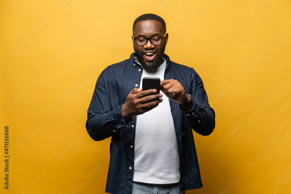 Foto de Portrait of cheerful young black guy sending message on mobile Foto de Portrait of cheerful young black guy sending message on mobile