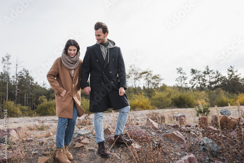 young couple in autumn outfit holding hands while walking outdoors
