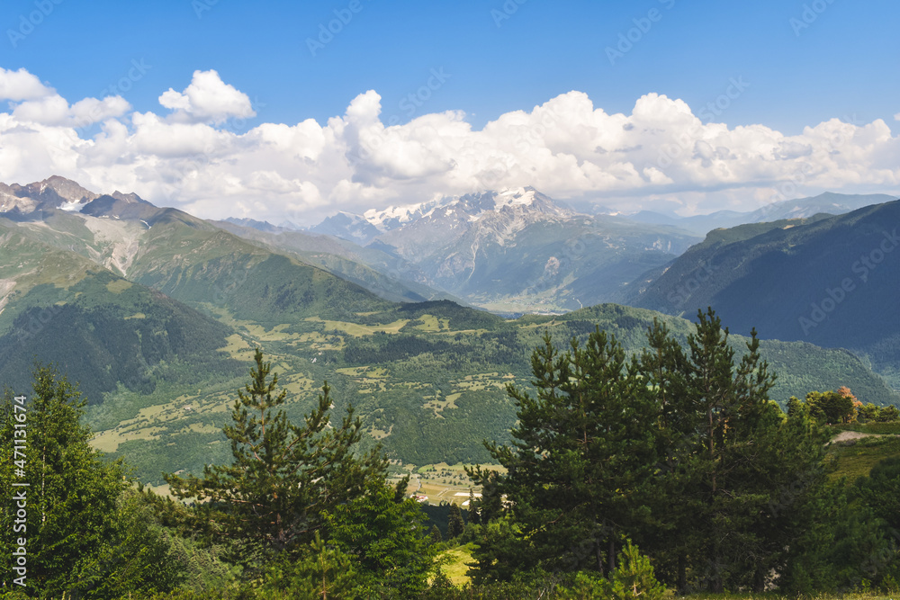 Summer mountain landscape near Mestia, Svaneti region, Georgia, Asia. Snowcapped mountains in the background. Blue sky with clouds above. Georgian travel destination