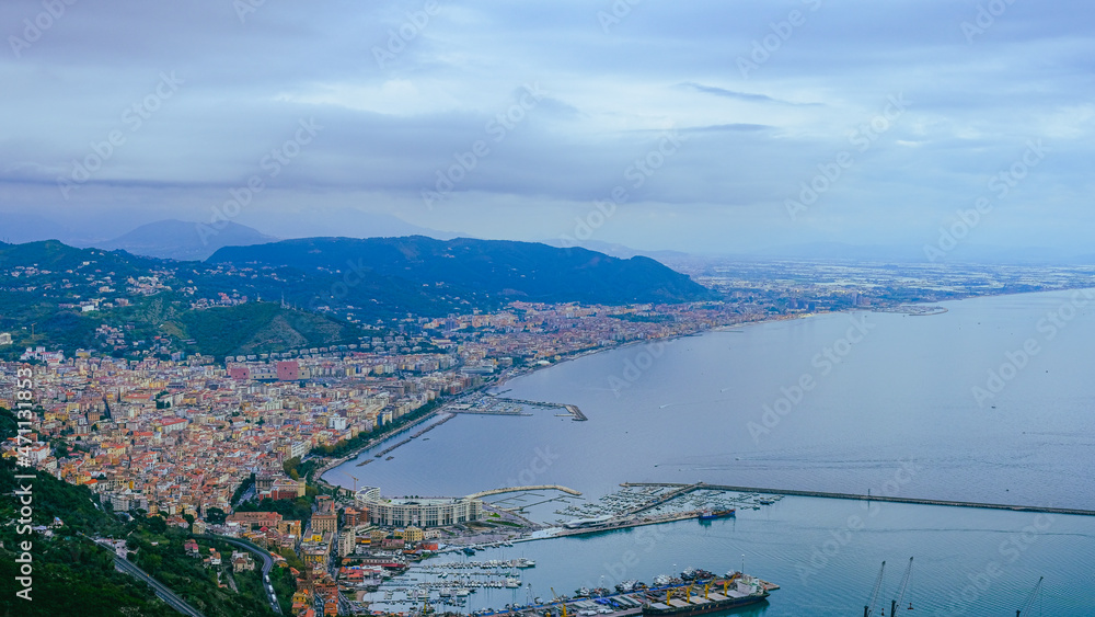 view from above of Salerno with harbor, piazza della libertà and mountains in the background