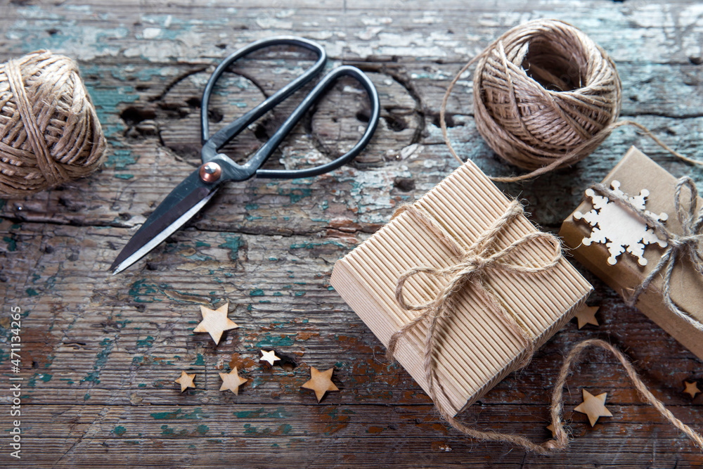 Two skeins of craft thread, scissors, two packed boxes, wooden stars lie on a wooden table