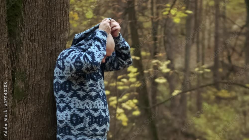 Portrait of a sad man leaning against a tree in an autumn park. The concept of melancholy, depression and bad mood Portrait of a sad man leaning against a tree in an autumn park. The concept of melancholy, depression and bad mood