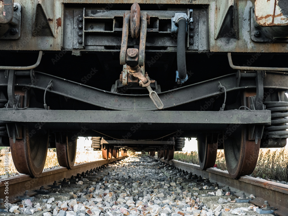 Bottom view of a train carriages forming a leak from the axles and wheels on the tracks to the bottom, with the ballast stones at the bottom Bottom view of a train carriages forming a leak from the axles and wheels on the tracks to the bottom, with the ballast stones at the bottom