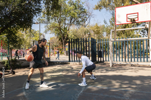Defendiendo en práctica de baloncesto entre dos jugadores latinos en cancha de la Ciudad de México