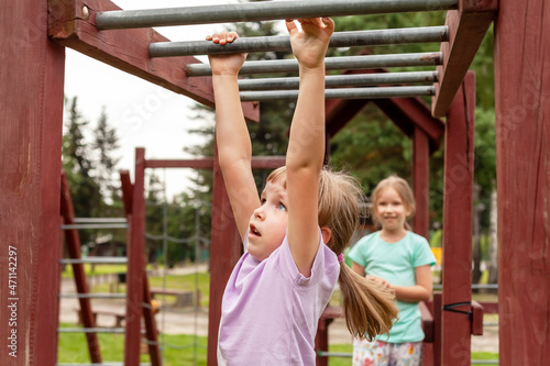 Elementary school age child exercising, climbing, playing on the playground, portrait, closeup. Children and healthy physical exercise and leisure activity outdoors simple concept, summer vacations