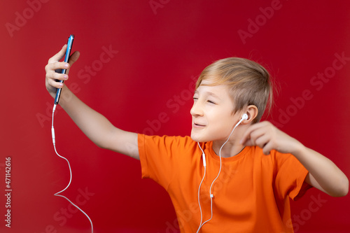cheerful boy holding a blue phone in front of him and talking by video call in he headphones