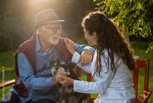 Nurse in white coat sitting on bench with senior man photo